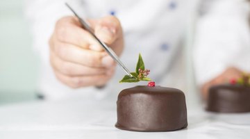 A pastry chef places a garnish on a chocolate tart