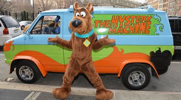 A man in a Scooby-Doo costume standing in front of a replica of the Mystery Machine van