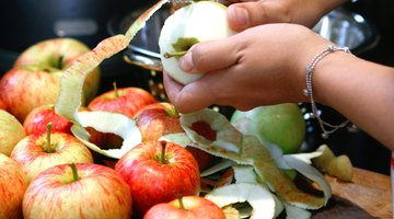 Woman using a knife to peel apples.