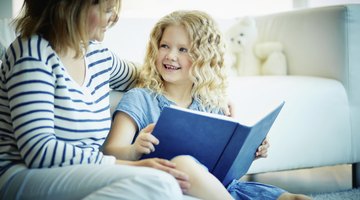 Parent sitting child on couch with book in hand
