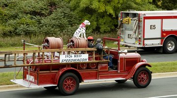 A Dalmatian sits on top of a fire engine.