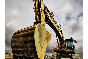 An excavator prepares to dig up at a construction site. An excavator prepares to dig up at a construction site.