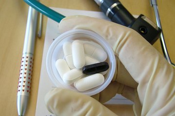 A doctor holds a cup of pills. A doctor holds a cup of pills.
