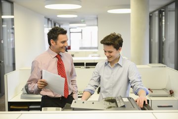 A young intern is working in a business office with a colleague. A young intern is working in a business office with a colleague.