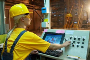 A female factory worker controlling equipment. A female factory worker controlling equipment.