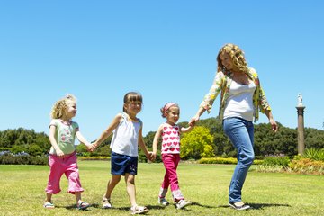 A nanny takes three girls to the park. A nanny takes three girls to the park.