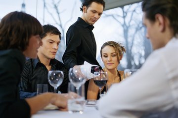 A server pours wine at a table. A server pours wine at a table.