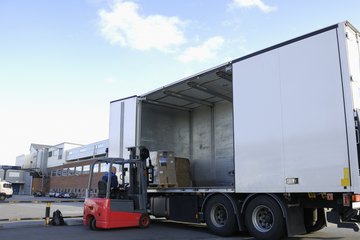A warehouseman unloads inventory from trucks that pull up into the warehouse's docking area. A warehouseman unloads inventory from trucks that pull up into the warehouse's docking area.