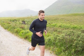 A fit man is jogging on a trail. A fit man is jogging on a trail.