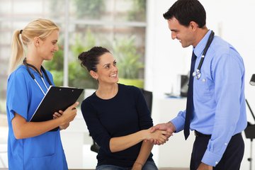A doctor and medical assistant talk to a happy patient A doctor and medical assistant talk to a happy patient