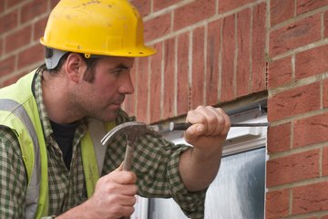 Builder using chisel to remove brick piece Builder using chisel to remove brick piece