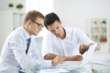 Image of two businessmen having a meeting and working over a laptop. Image of two businessmen having a meeting and working over a laptop.