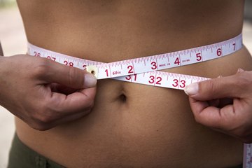 A measuring tape around a woman's waist. A measuring tape around a woman's waist.