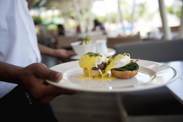 A waiter carrying two plates to a table. A waiter carrying two plates to a table.