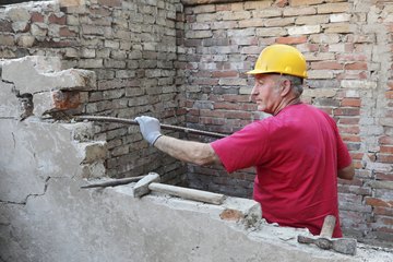 Man using a jointer on a old brick wall Man using a jointer on a old brick wall