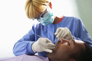 A dental hygienist cleans a patients teeth. A dental hygienist cleans a patients teeth.