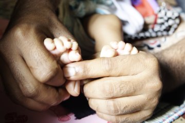 Neonatal nurse holding premature infant's feet Neonatal nurse holding premature infant's feet
