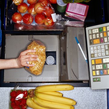 Grocery clerk scanning items at checkout counter, overhead view