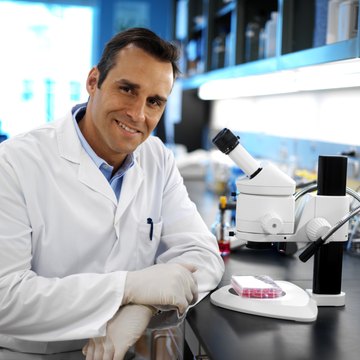 portrait of a young doctor sitting beside a microscope