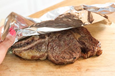 Covering rib steak with foil.