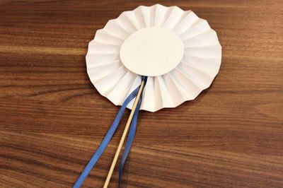 Hot glue a dowel and ribbon to the rosette