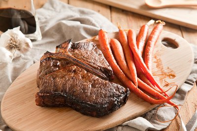 Cooked steak resting on a cutting with a side of cooked carrots.