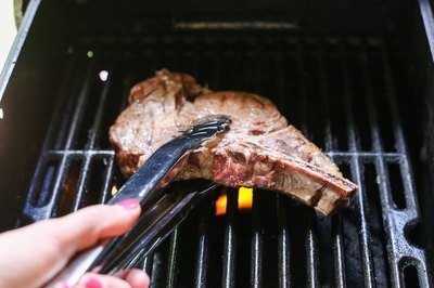 Turning rib steak on grill.