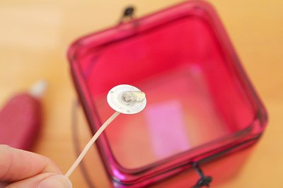 Secure the wick to the container with hot glue.