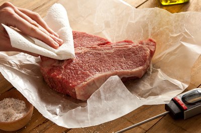 Raw steak pat down with paper towels.