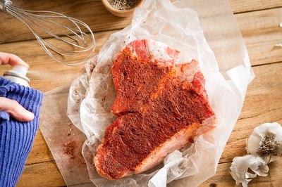 Raw t-bone steak sprayed with cooking oil.