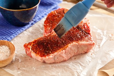 Raw t-bone steak brushed with marinade.