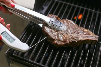 Grasping rib steak with tongs.