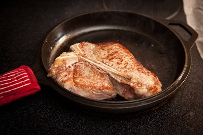 Steak cooking in a cast-iron skillet.