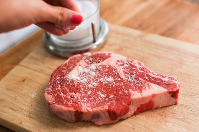 Salting a rib steak.