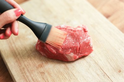 Brushing oil on a top sirloin steak.
