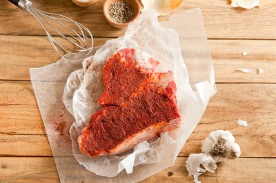 Raw t-bone steak coated in dry spices.