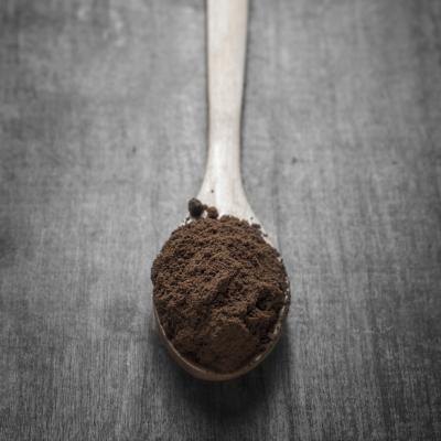 Fine coffee grounds on wooden spoon