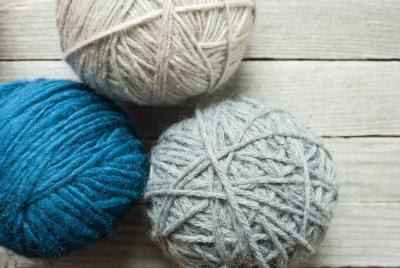 A loom and shuttle weaves yarn into a piece of fabric.