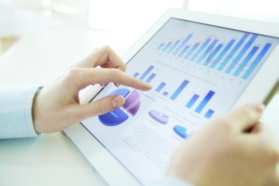 Close up of hands using a tablet with statistics on the display.