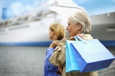 Two woman with shopping bags stand at a port in front of a cruise ship.