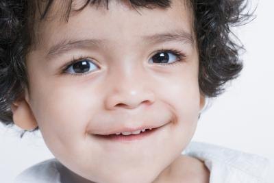 Close up of smiling boy with curly hair and angular face.
