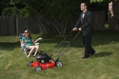 Man in suit mowing lawn slowly.