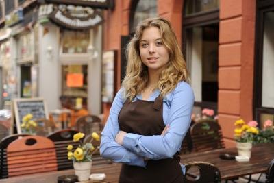 A waitress stands in front of outdoor tables.