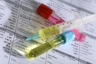 Close up of syringe and test tubes on medical chart.