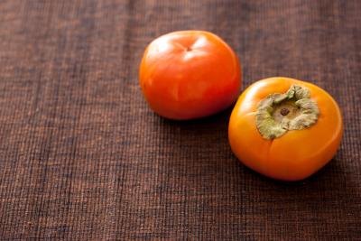2 persimmons on a brown background.