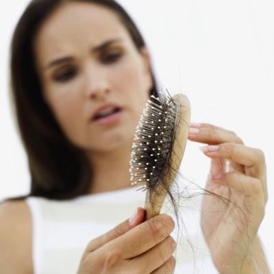 Woman looking at brush full of hair.