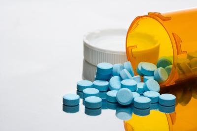 Prescription bottle with blue pills spilling out.
