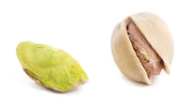 Two pistachios one shelled, and one without the shell.