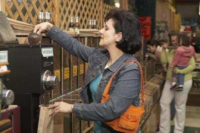 Woman pouring coffee beans into grinder at supermarket