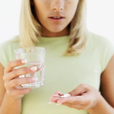 Close up of a woman with pills and a glass of water.